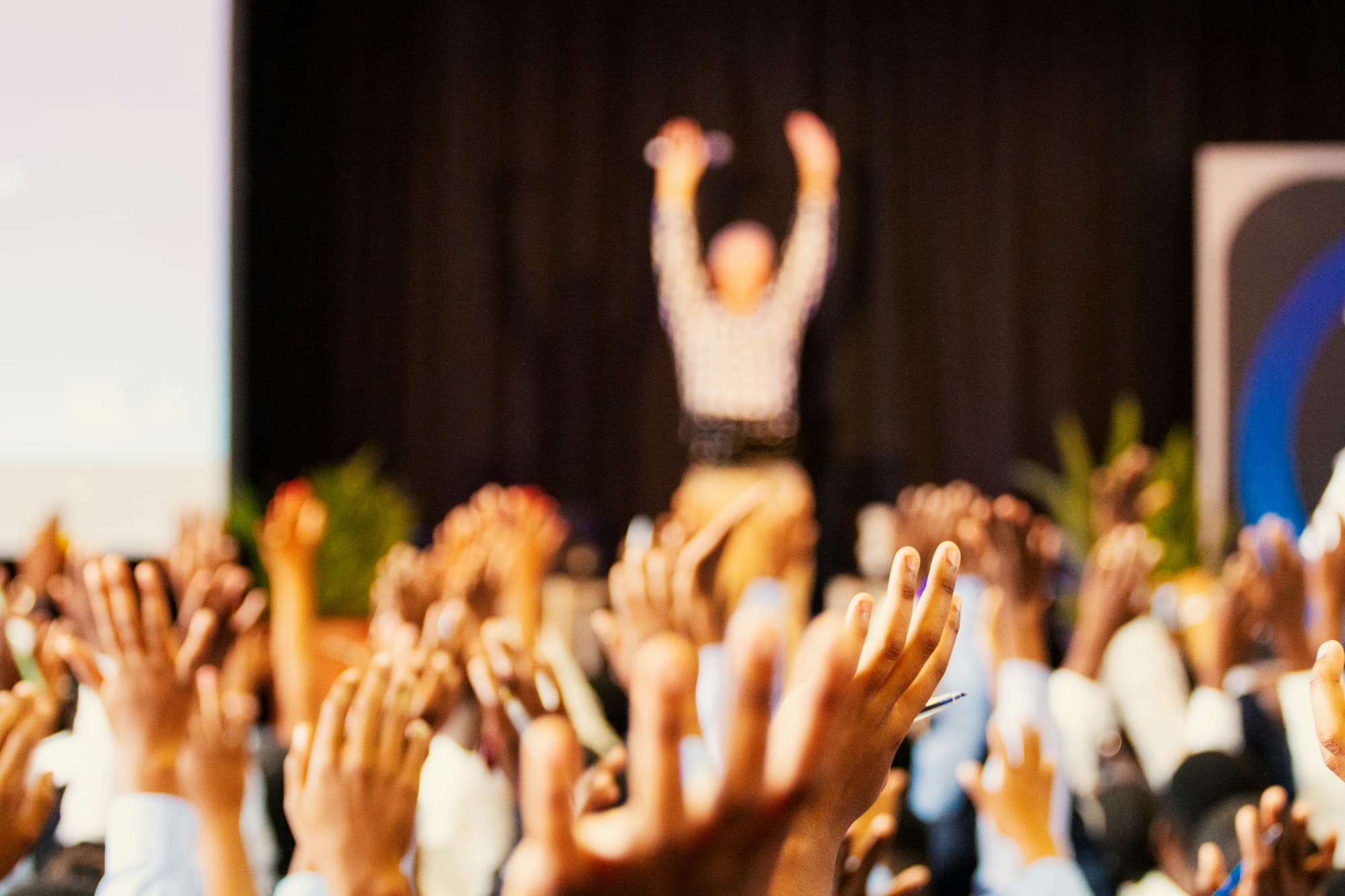 A room of people with their hands in the air